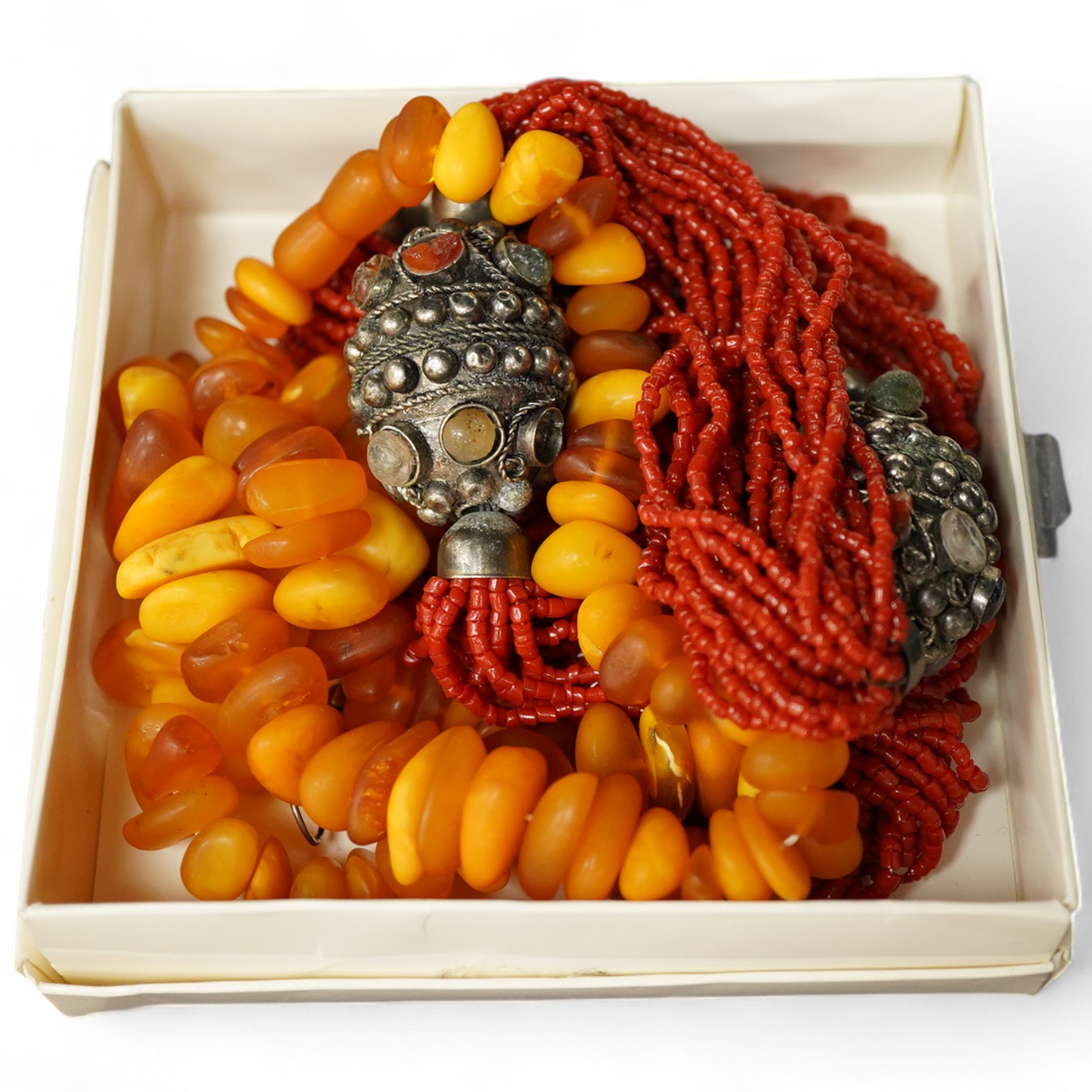 Two necklaces, comprising: a multi-strand coral necklace of torsade design, spaced by beads set with various hardstones, length 73cm; and an amber bead necklace, length 57cm